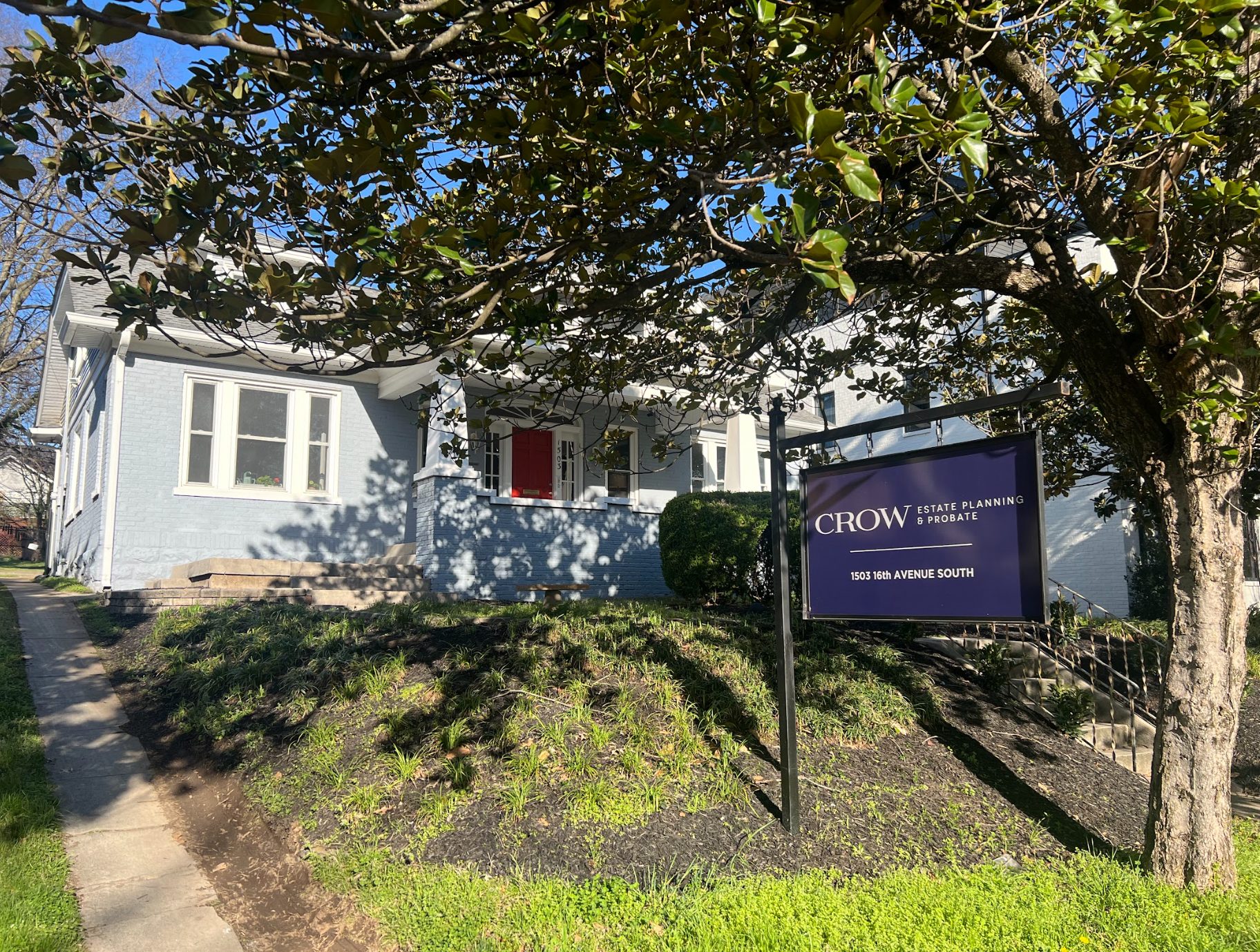 A blue house in Nashville with a sign in front of it reading "Crow Estate Planning & Probate 1503 16th Avenue South."